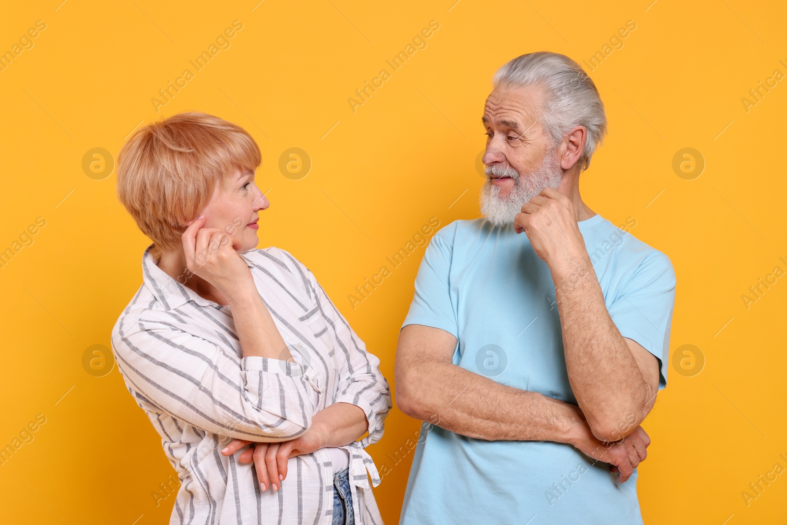 Photo of Lovely senior couple looking at each other on orange background