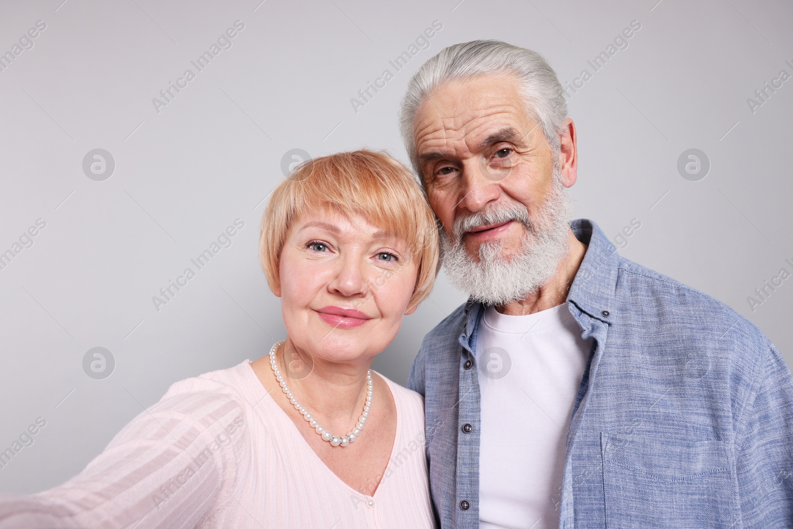 Photo of Lovely senior couple taking selfie on grey background