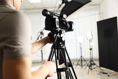 Man with professional video camera in studio, closeup. Space for text