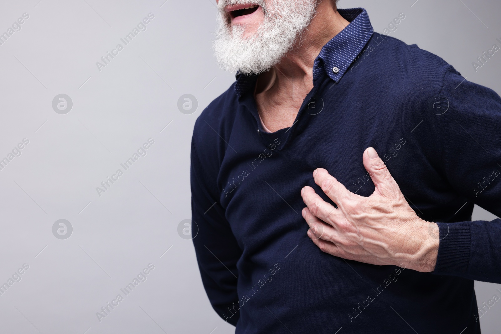 Photo of Heart attack. Senior man suffering from pain in chest on grey background, closeup. Space for text