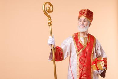 Photo of Saint Nicholas with gift on beige background. Space for text