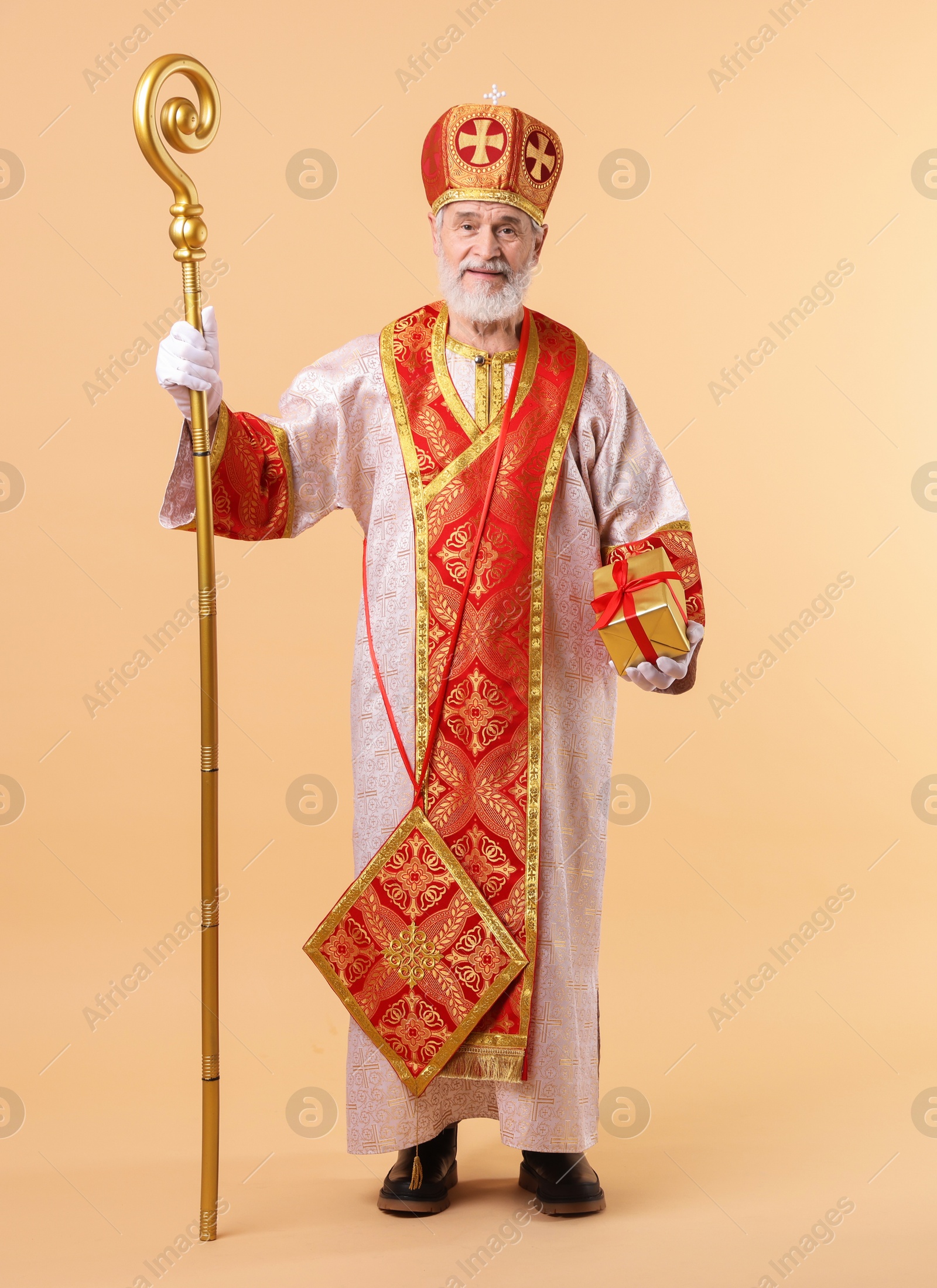 Photo of Saint Nicholas with gift on beige background. Space for text