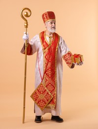 Photo of Saint Nicholas with gift on beige background. Space for text