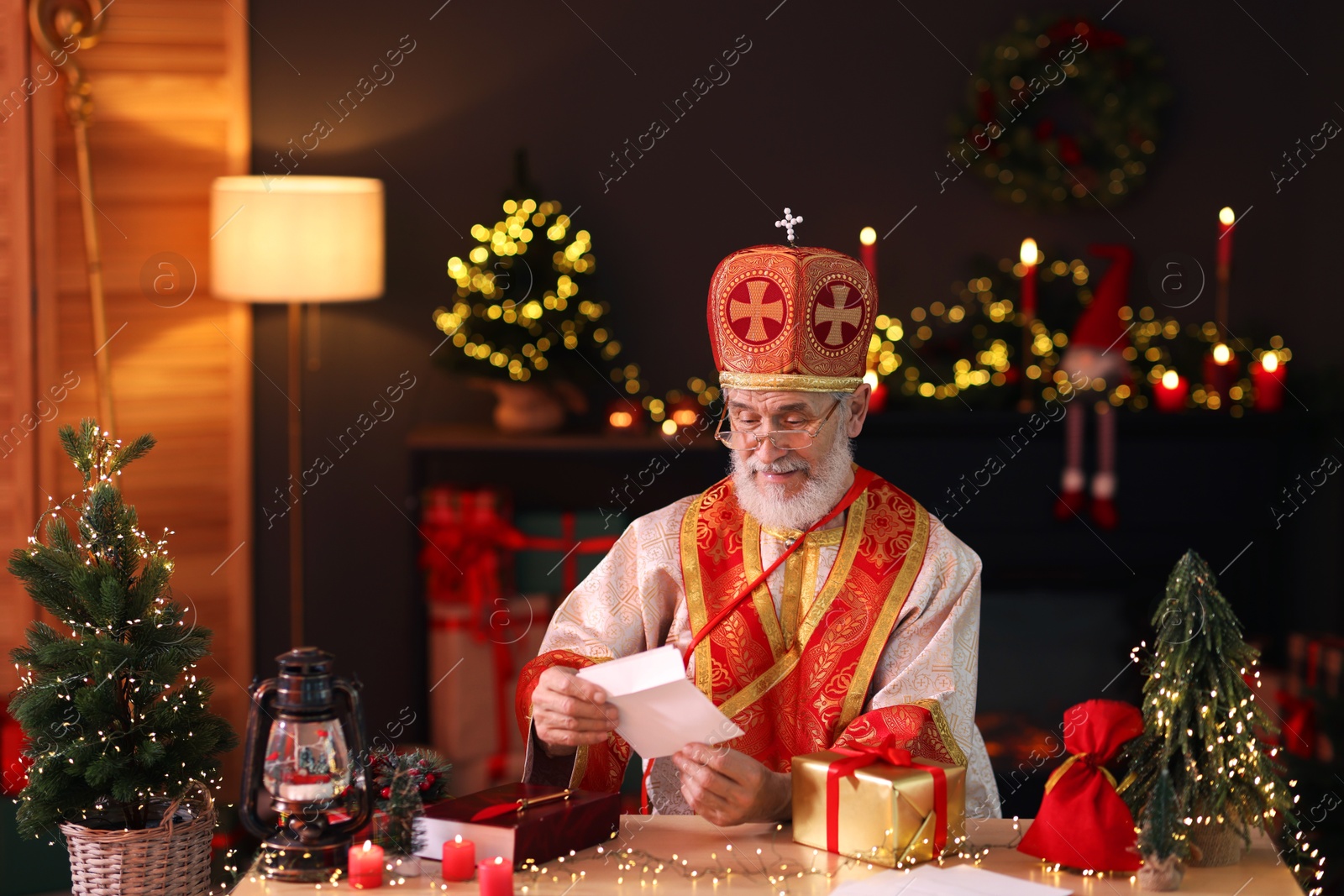 Photo of Saint Nicholas with letter at desk in room decorated for Christmas