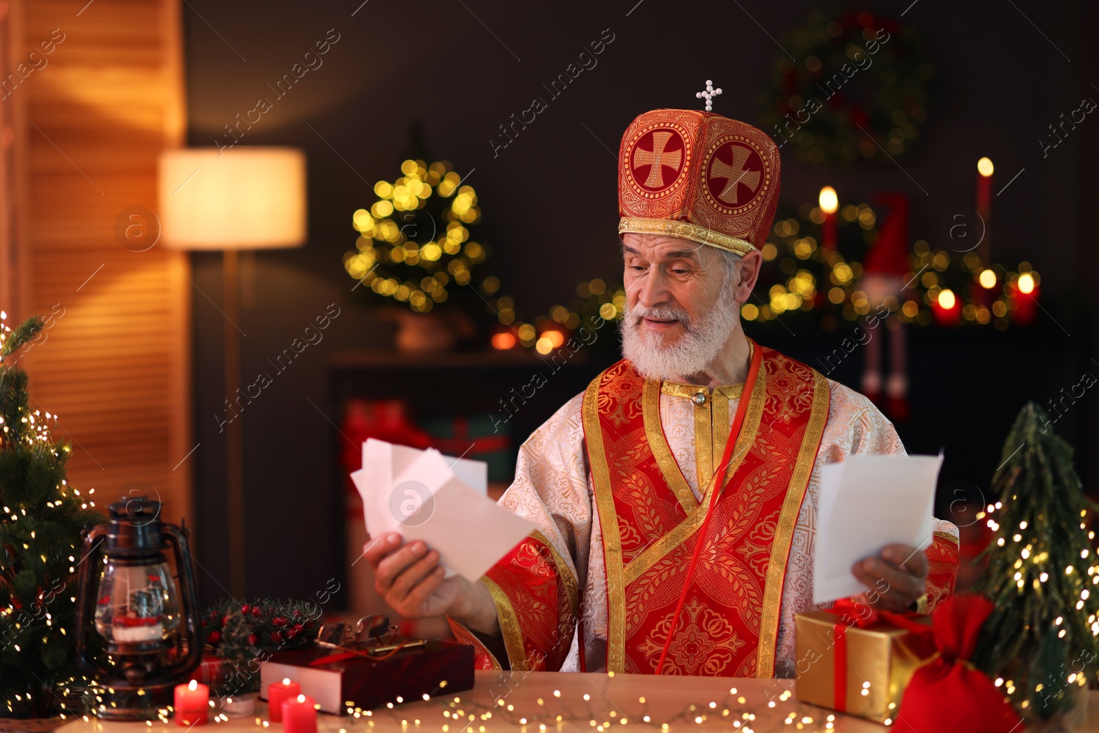 Photo of Saint Nicholas with letters at desk in room decorated for Christmas