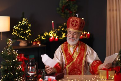 Photo of Saint Nicholas with letters at desk in room decorated for Christmas