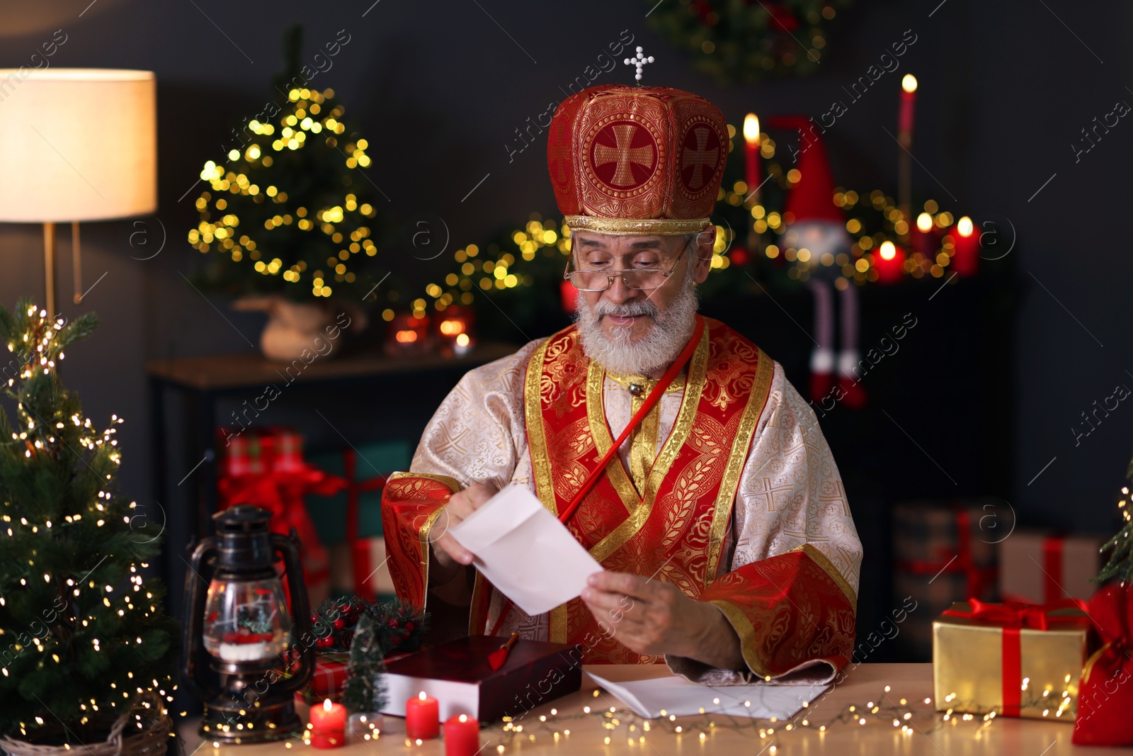 Photo of Saint Nicholas with letters at desk in room decorated for Christmas