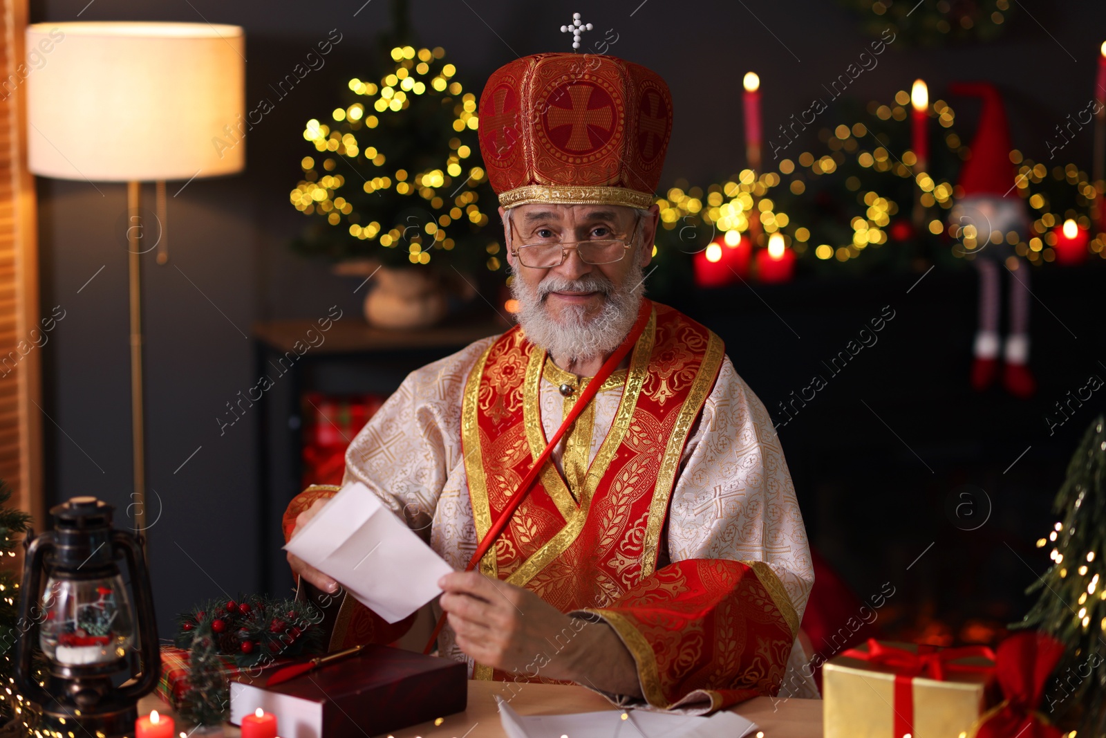 Photo of Saint Nicholas with letter at desk in room decorated for Christmas