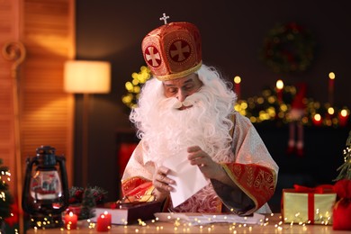 Photo of Saint Nicholas with letters at desk in room decorated for Christmas