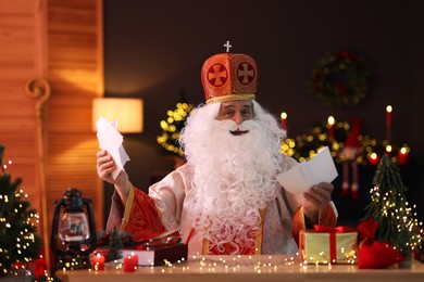 Photo of Saint Nicholas with letters at desk in room decorated for Christmas