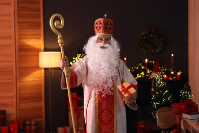 Photo of Saint Nicholas with gift in room decorated for Christmas