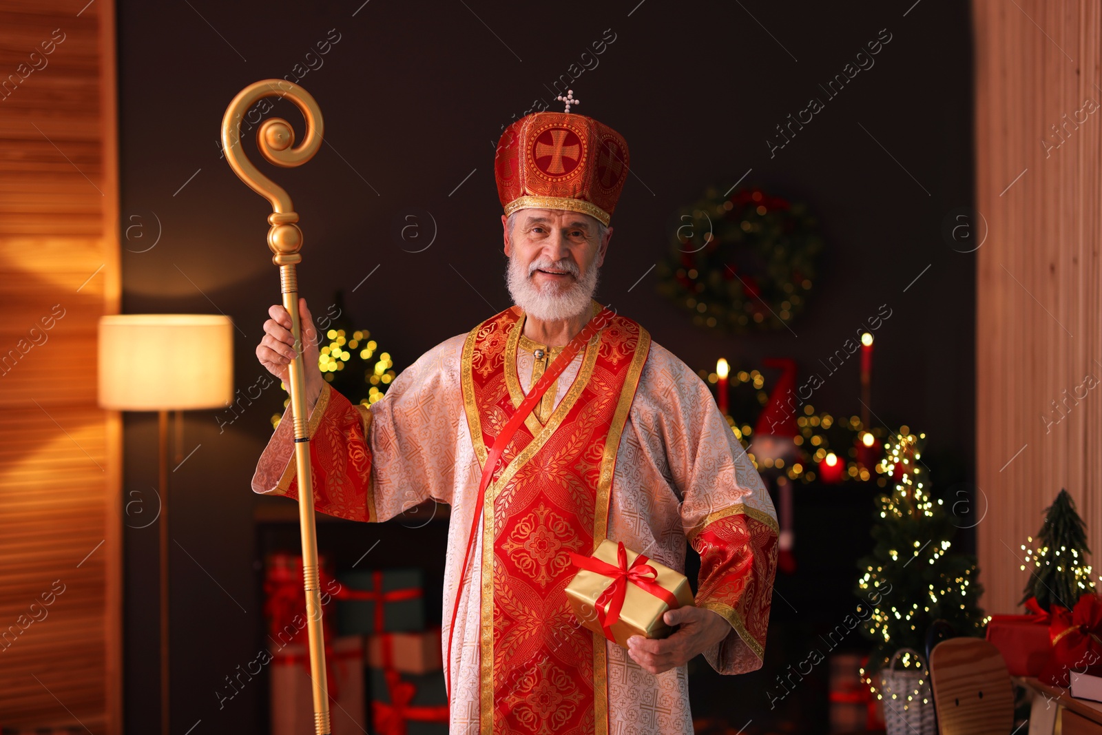 Photo of Saint Nicholas with gift in room decorated for Christmas