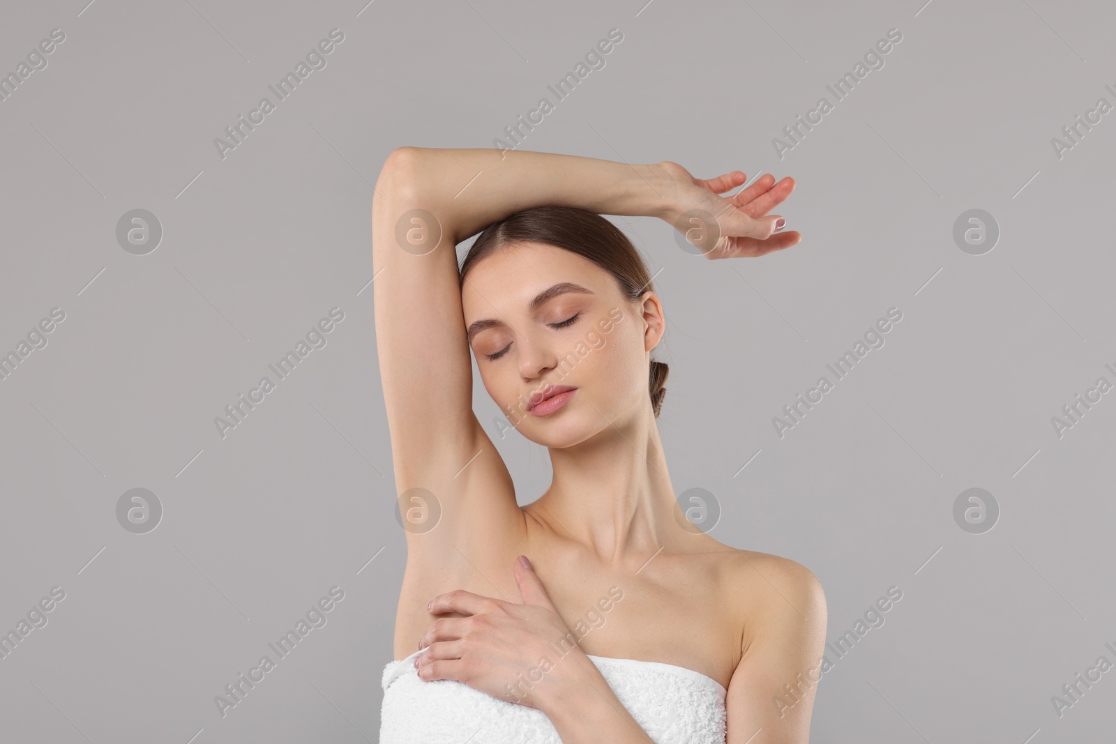 Photo of Young woman showing smooth skin after epilation on gray background