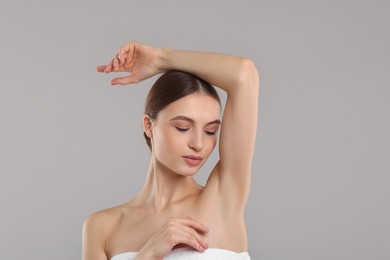 Photo of Young woman showing smooth skin after epilation on gray background