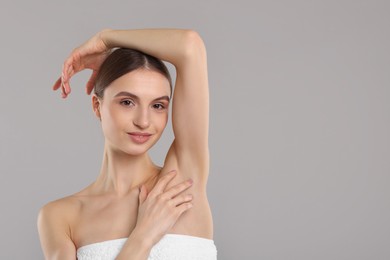 Photo of Young woman showing smooth skin after epilation on gray background, space for text