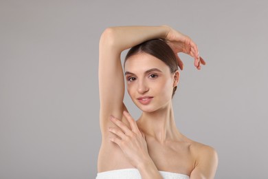 Photo of Young woman showing smooth skin after epilation on gray background