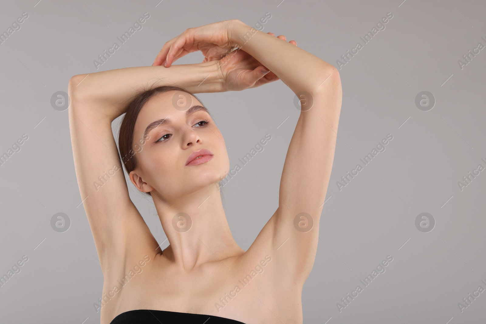 Photo of Young woman showing smooth skin after epilation on gray background