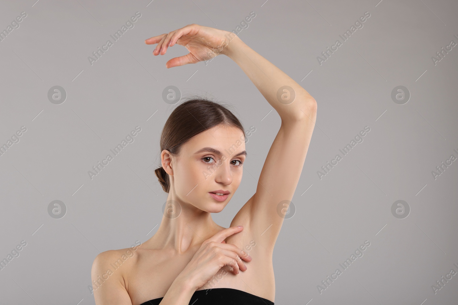 Photo of Young woman showing smooth skin after epilation on gray background