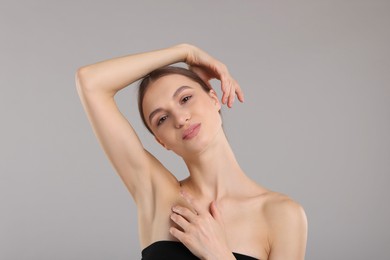 Photo of Young woman showing smooth skin after epilation on gray background