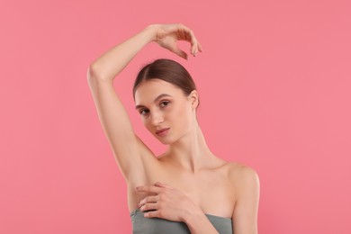 Photo of Young woman showing smooth skin after epilation on pink background