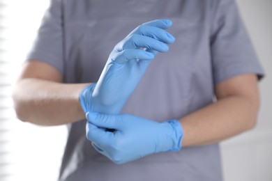 Photo of Medical worker putting on gloves in hospital, closeup