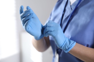 Photo of Medical worker putting on gloves in hospital, closeup