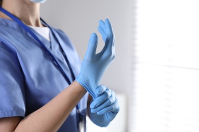 Photo of Medical worker putting on gloves in hospital, closeup. Space for text