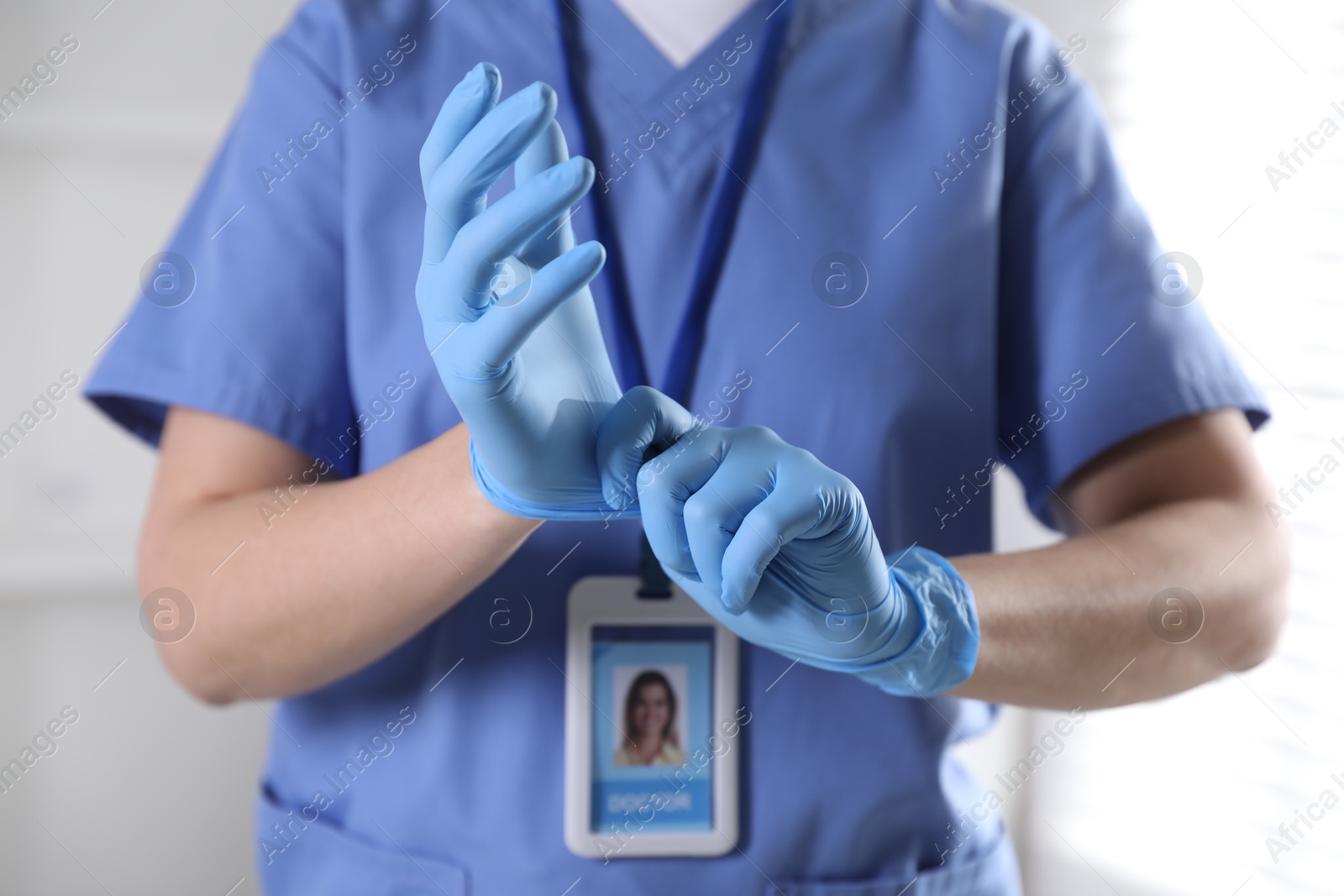 Photo of Medical worker putting on gloves in hospital, closeup