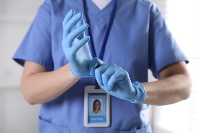 Photo of Medical worker putting on gloves in hospital, closeup