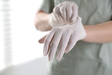 Photo of Medical worker putting on gloves in hospital, closeup