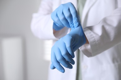 Photo of Medical worker putting on gloves in hospital, closeup