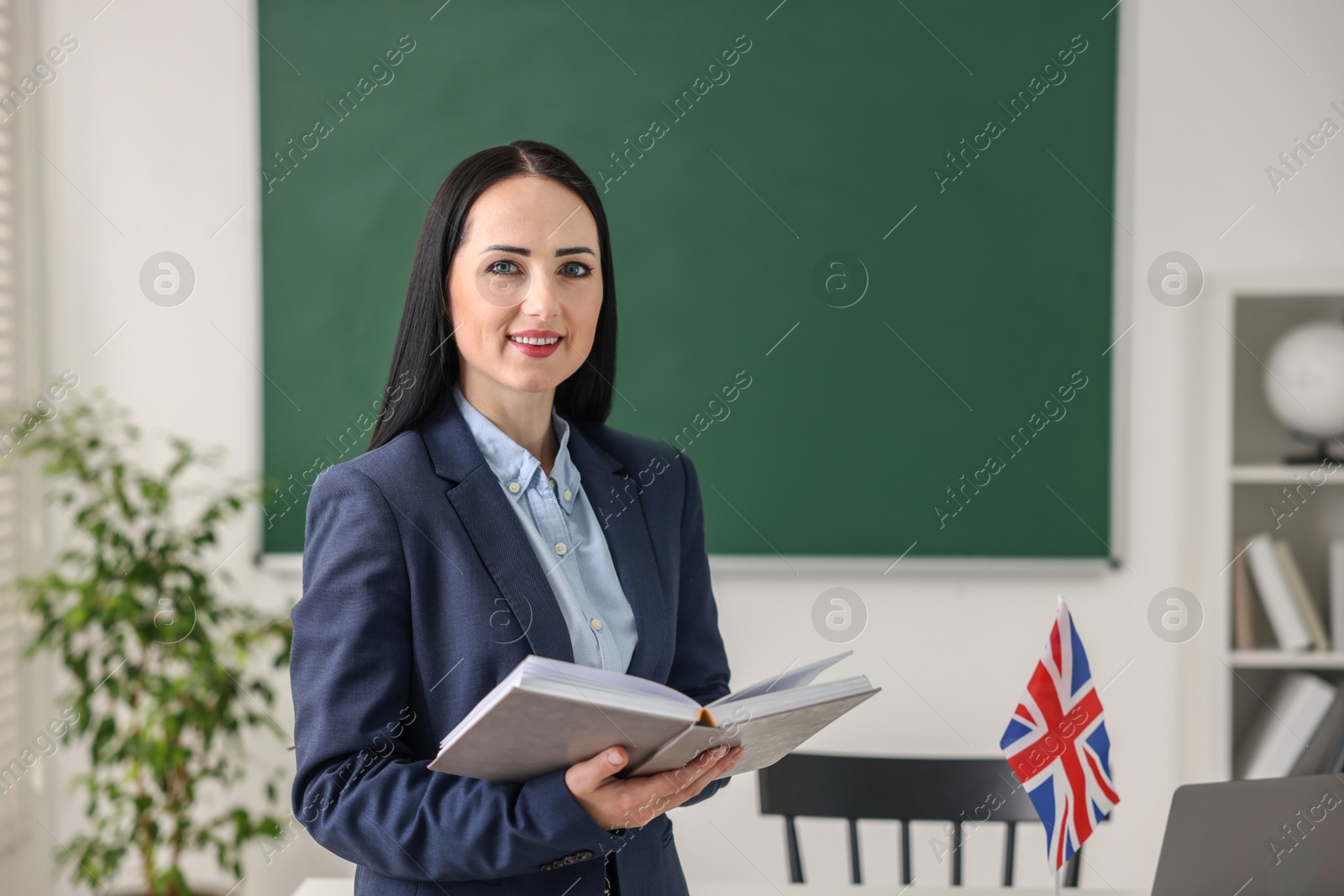 Photo of English teacher with book in classroom. Space for text