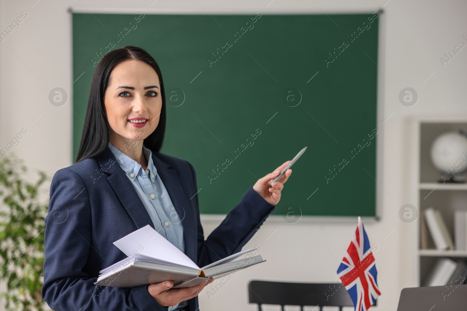 Photo of English teacher with book in classroom. Space for text