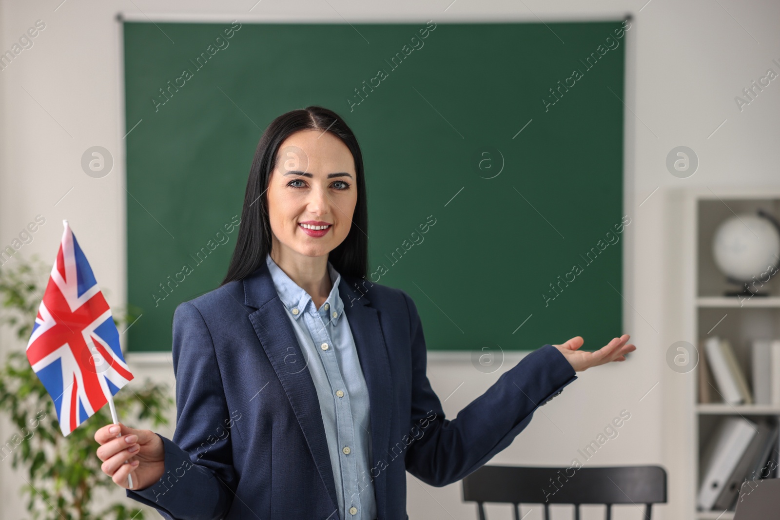 Photo of English teacher with UK flag in classroom. Space for text