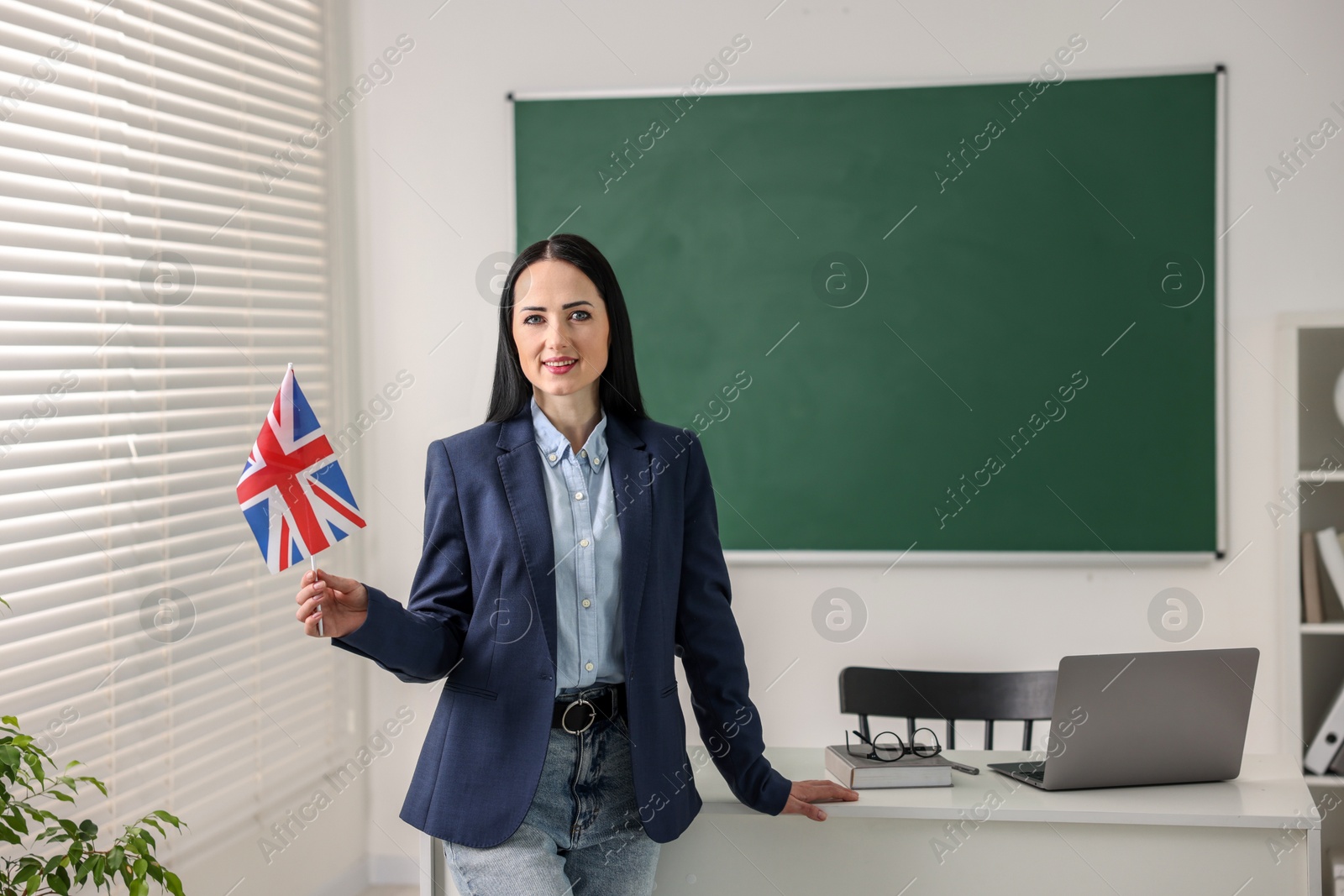 Photo of English teacher with UK flag in classroom. Space for text