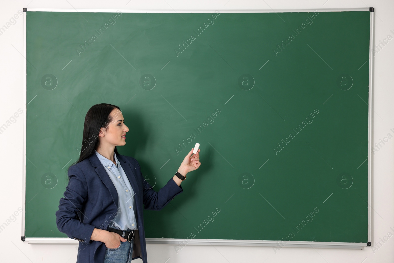 Photo of English teacher near chalkboard in classroom. Space for text