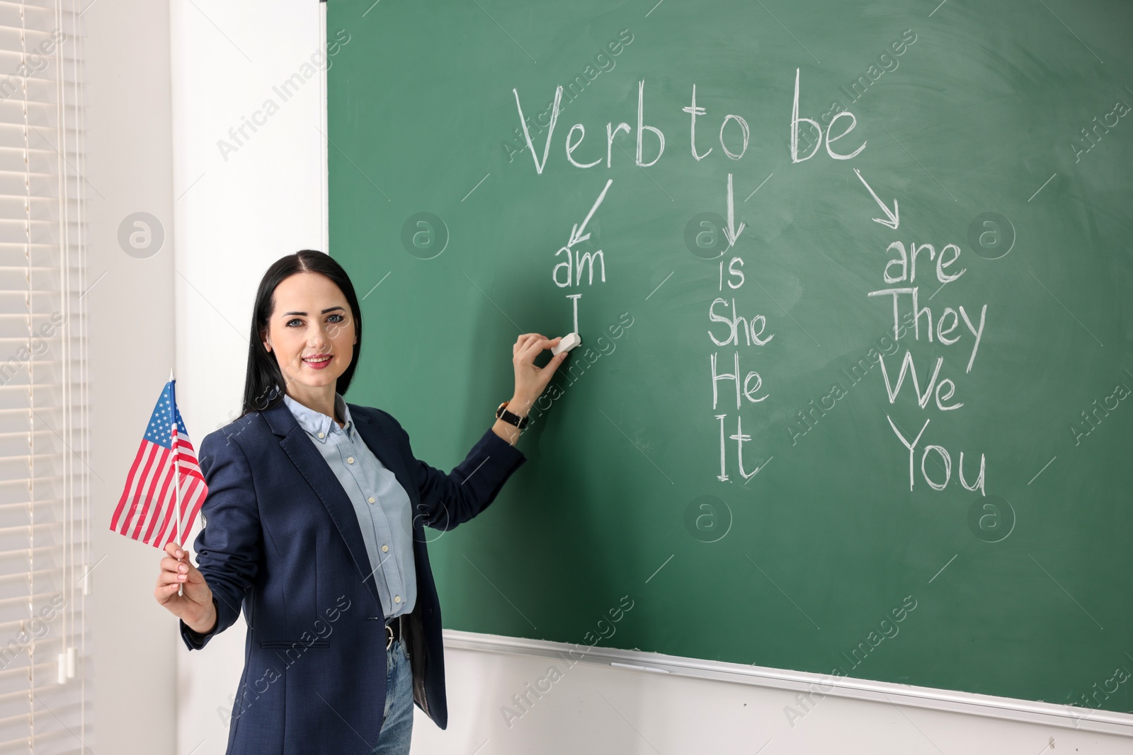 Photo of English teacher during lesson near chalkboard in classroom