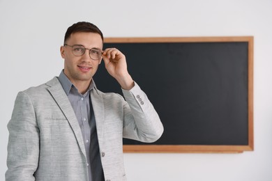 Photo of English teacher against blackboard in classroom. Space for text