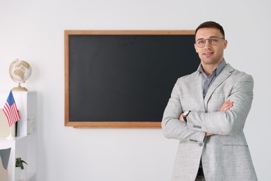 Photo of English teacher against blackboard in classroom. Space for text