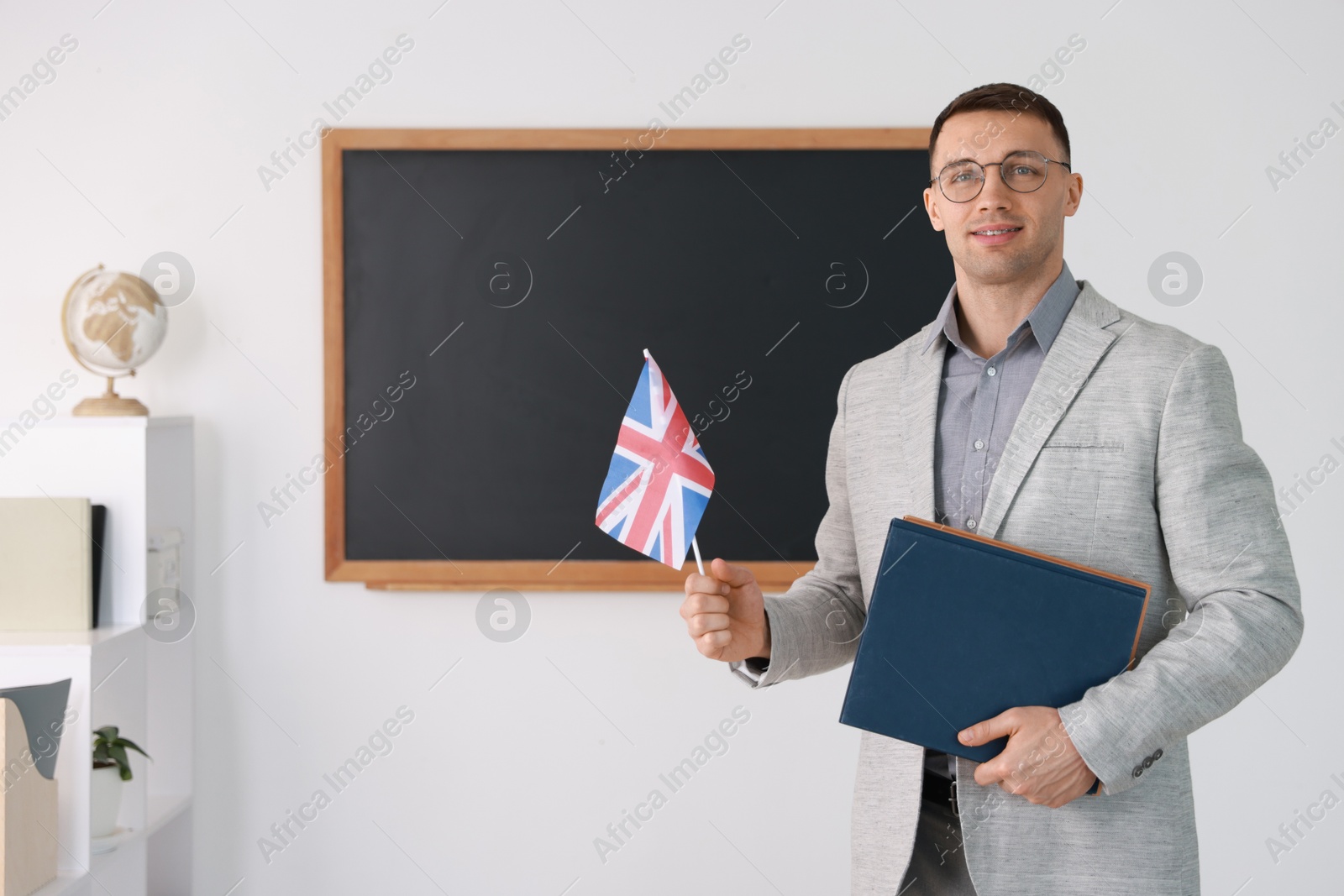 Photo of English teacher with UK flag against blackboard in classroom