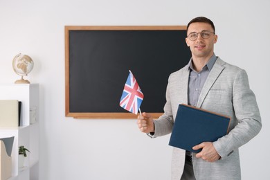 Photo of English teacher with UK flag against blackboard in classroom