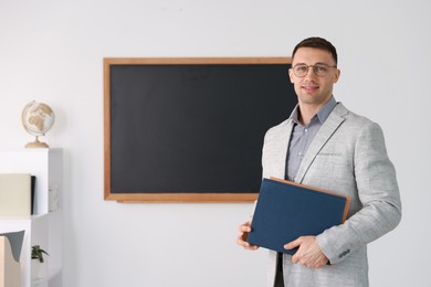 Photo of English teacher with books against blackboard in classroom. Space for text