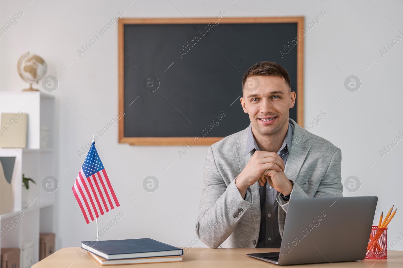 Photo of English teacher working at desk in classroom. Space for text