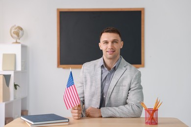 Photo of English teacher with American flag at desk in classroom