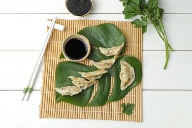 Photo of Tasty boiled gyoza (dumplings) served on white wooden table, flat lay