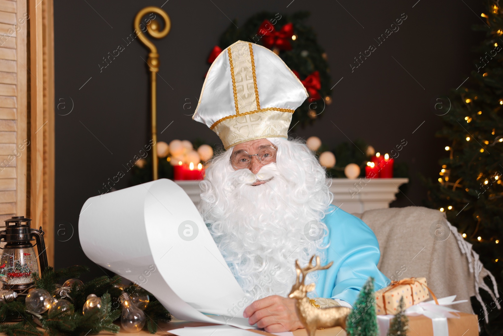 Photo of Saint Nicholas with wish list in room decorated for Christmas