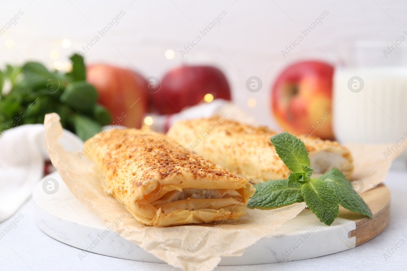 Photo of Tasty apple strudels and mint on light table, closeup