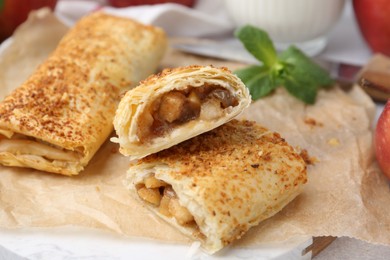 Tasty apple strudels and mint on table, closeup