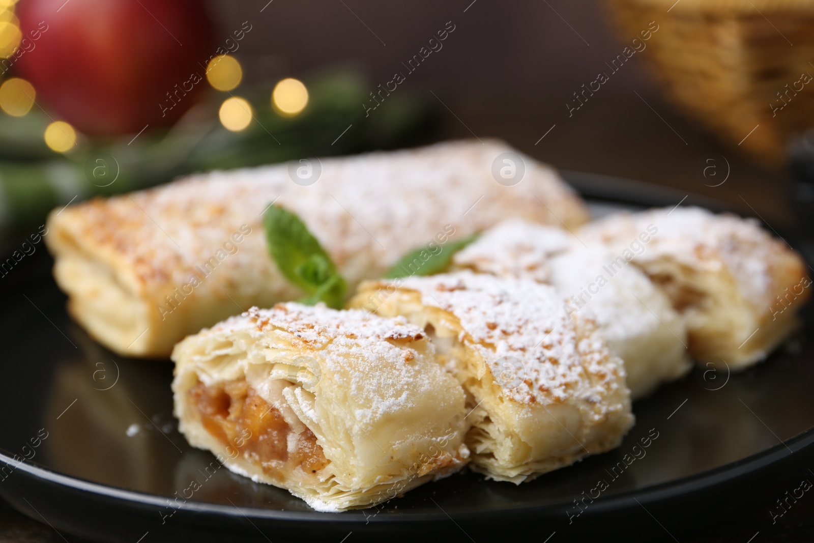 Photo of Tasty apple strudels with powdered sugar and mint on table, closeup