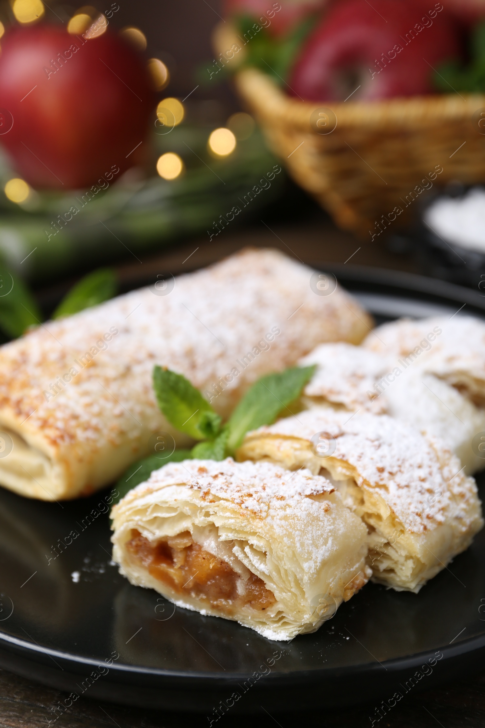 Photo of Tasty apple strudels with powdered sugar and mint on table, closeup